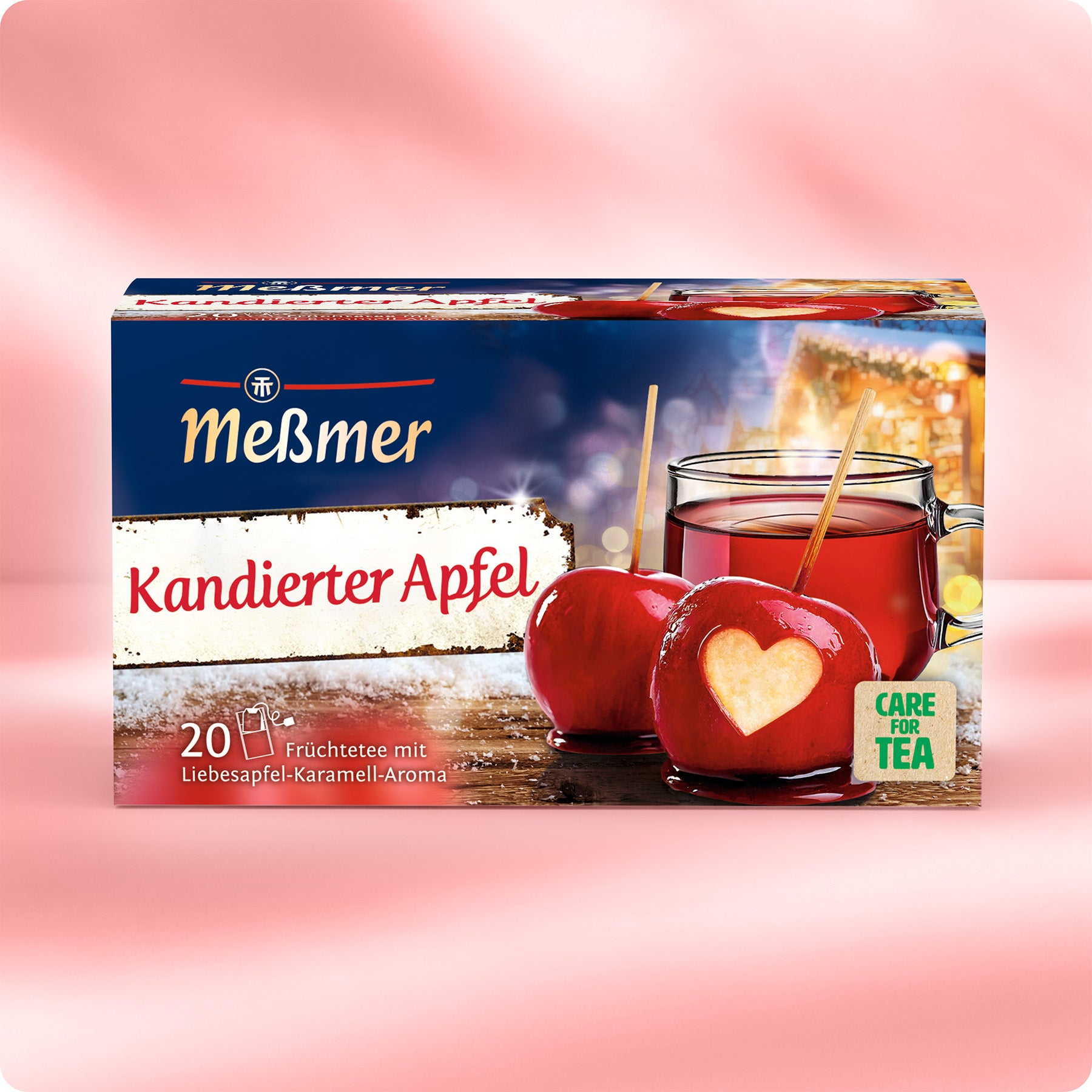 Verpackung von Meßmer Kandierter Apfel mit 20 Teebeuteln, abgebildet mit glühweinfarbenem Tee und roten kandierten Äpfeln mit Herzmuster vor weichem rosafarbenem Hintergrund.
