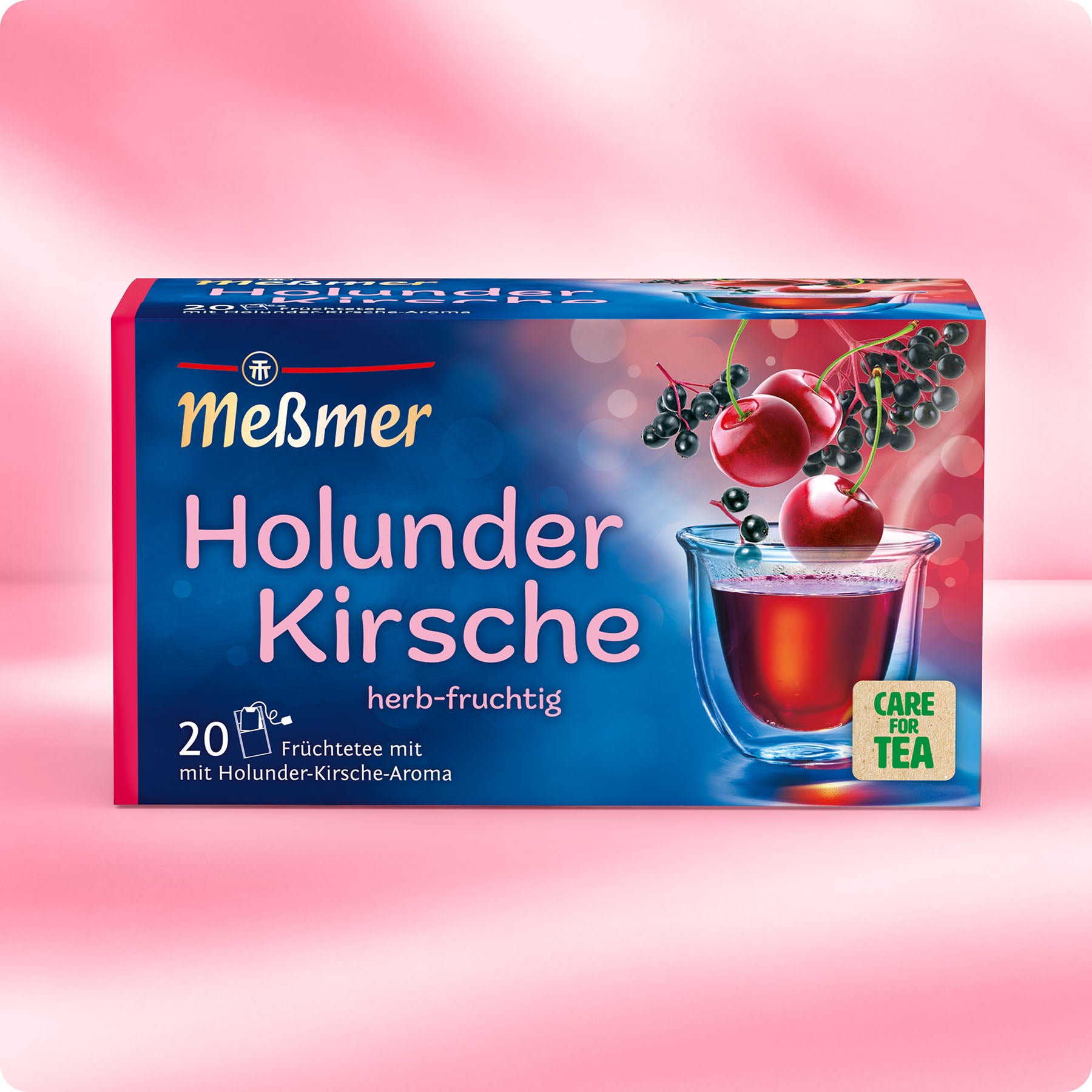 Verpackung des Holunder-Kirsche Früchtetees von Meßmer mit Kirschen und Holunderbeeren vor rosa Hintergrund, zeigt eine Tasse mit rotem Tee und 20 Teebeuteln.