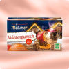 Verpackung von Winterpunsch mit Glühwein-Aroma, Tee aus Früchten, Apfel, Zimtstangen, Sternanis und getrockneter Orangenscheibe vor stimmungsvoller Winterkulisse.