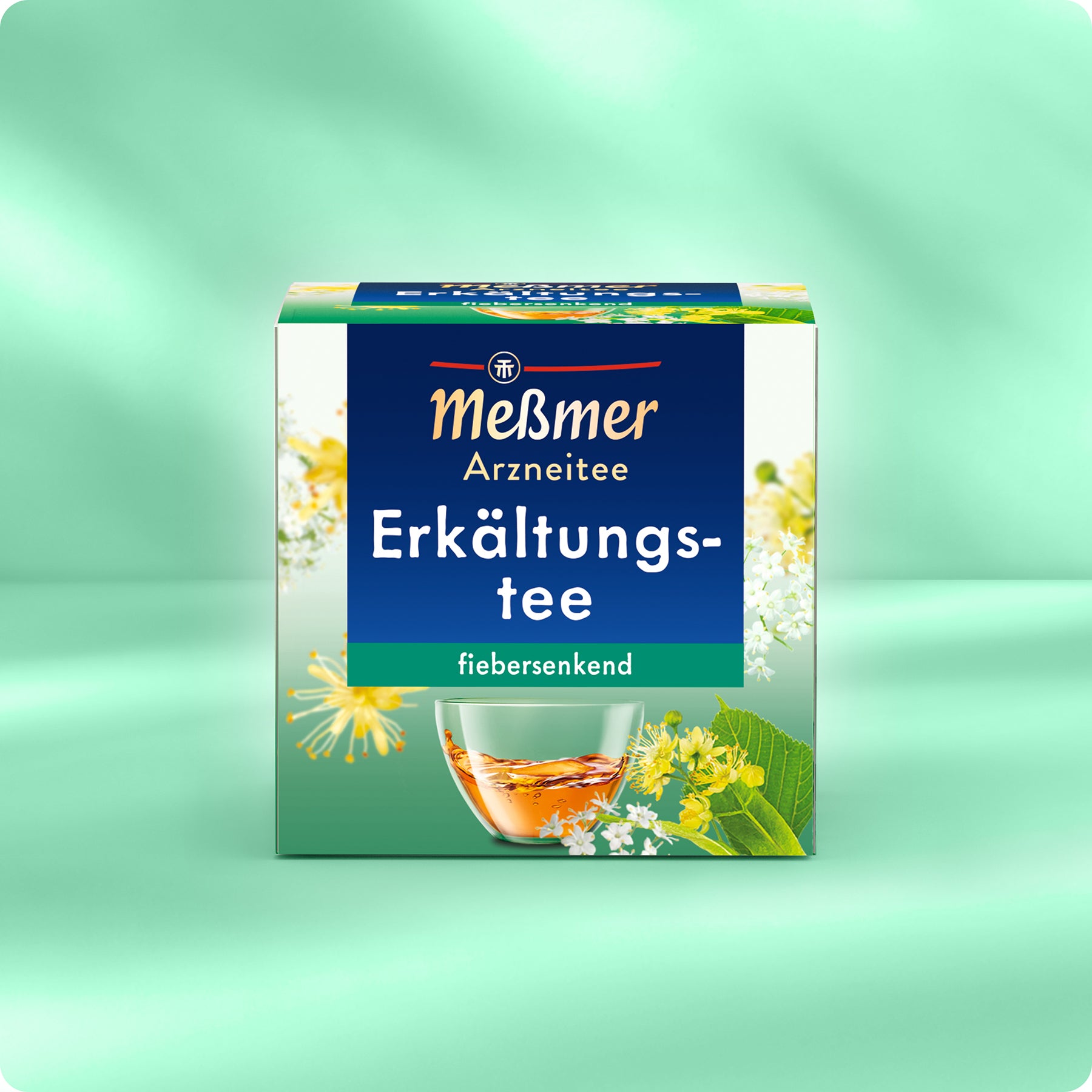 Eine Schachtel Meßmer DE Erkältungstee, ein pflanzliches Arzneimittel für fiebrige Erkältungen, ist mit Blumen und einem Glas Tee auf Grün abgebildet. Die Verpackung hebt seine fiebersenkende Wirkung hervor.