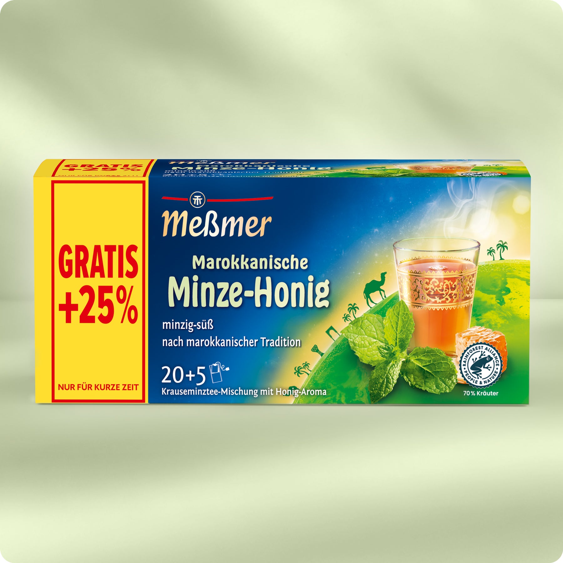 Eine Schachtel Meßmer Marokkanischer Minz-Honig-Tee mit 25% Gratiszugabe. Die Schachtel zeigt ein Glas Tee, Minzblätter und eine Wüstenszene mit Kamelen und Palmen. Der Text hebt 20+5 Teebeutel und die marokkanische Tradition hervor.
