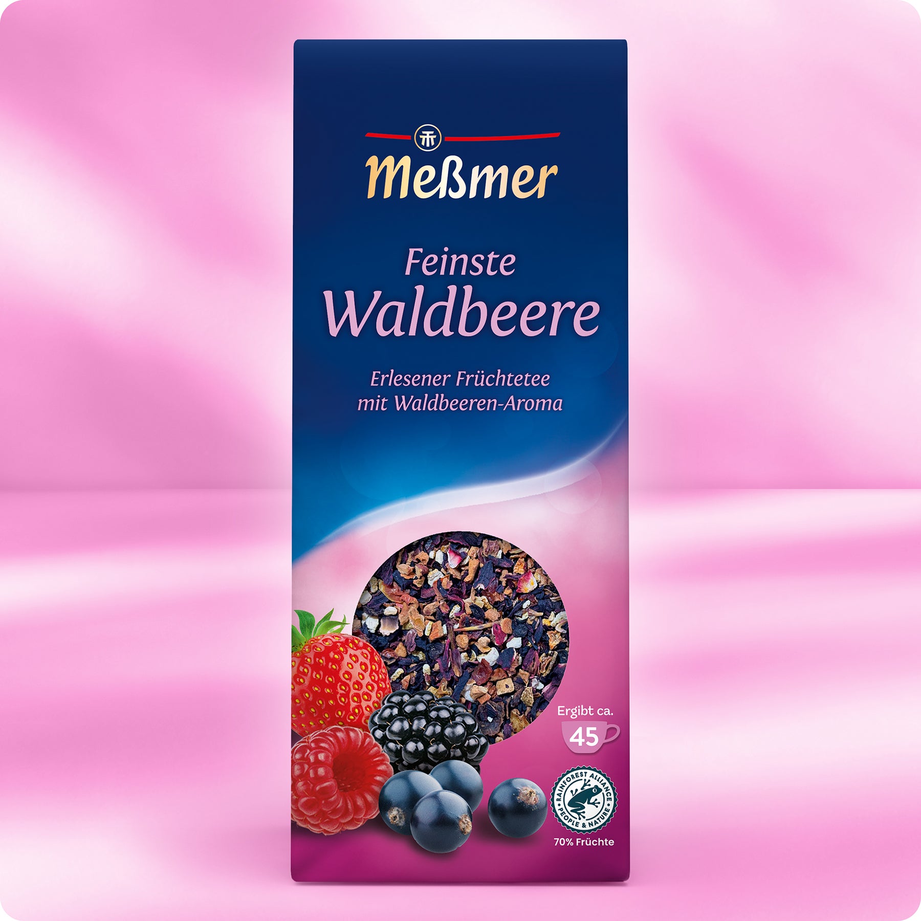 Eine Schachtel Meßmer DE Waldbeere Tee auf rosa Hintergrund mit Erdbeeren, Himbeeren, Brombeeren und Blaubeeren auf der Vorderseite und einem Fenster, das den Blick auf die Trockenfrüchteteemischung im Inneren freigibt.