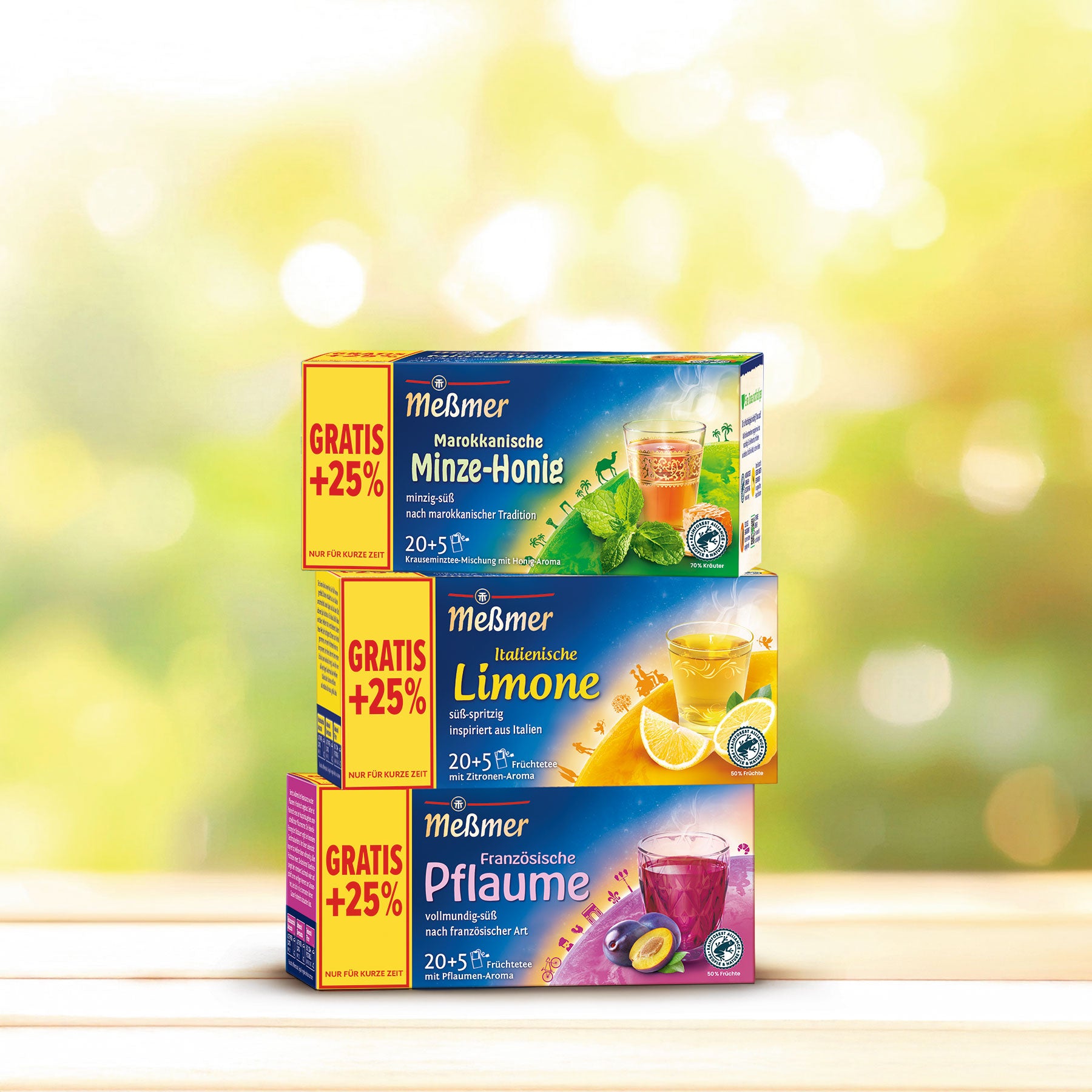 Drei bunte Tee-Schachteln mit verschiedenen Frucht- und Kräutergeschmacksrichtungen auf hellem Hintergrund gestapelt.