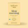 Verpackung von Bio Slow Morning mit Bio-Siegel, Sonnenmotiv und Hinweis auf grünen Tee mit Matcha und Lemongras, präsentiert auf hellem, warmem Hintergrund für einen entspannenden Start.
