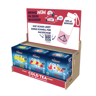 Das Meßmer DE Cold Tea Bestseller Set im Aufsteller präsentiert verschiedene Sorten zur Selbstbedienung; ein Schild mit Wasserflasche, Teebeuteln, QR-Code und deutschem Text informiert über das Getränkeangebot.